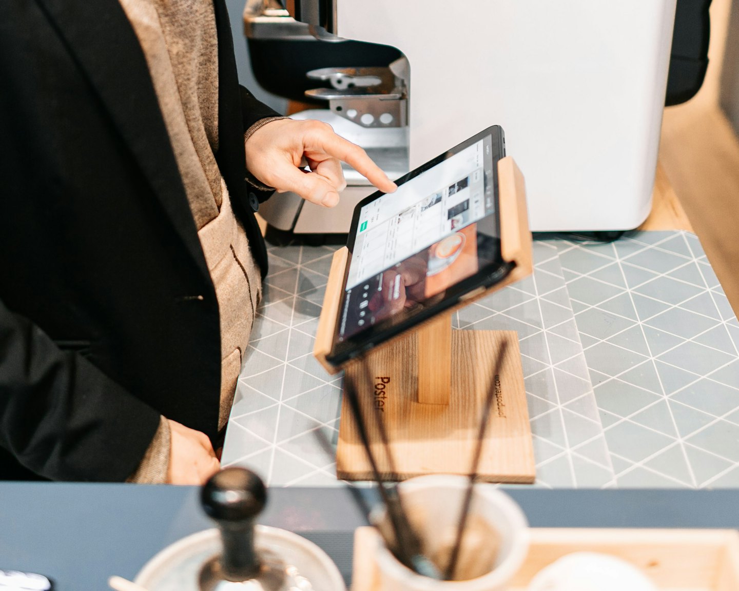 Hand using a digital tablet at a business counter.